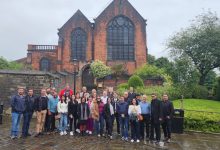 Grupo de participantes do evento 'Missão Raízes do Cooperativismo' em Manchester, Inglaterra, posando em frente ao Museu dos Pioneiros em Rochdale