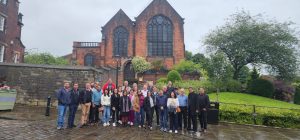 Grupo de participantes do evento 'Missão Raízes do Cooperativismo' em Manchester, Inglaterra, posando em frente ao Museu dos Pioneiros em Rochdale