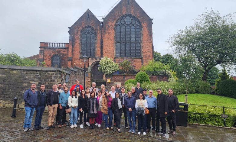 Grupo de participantes do evento 'Missão Raízes do Cooperativismo' em Manchester, Inglaterra, posando em frente ao Museu dos Pioneiros em Rochdale