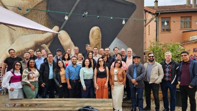 Integrantes da 'Missão Raízes do Cooperativismo' posam para uma foto em frente a uma obra de arte urbana durante sua visita à cooperativa Les Relais Solidaires em Paris, destacando o intercâmbio cultural e a aprendizagem em sua jornada pelo conhecimento cooperativo