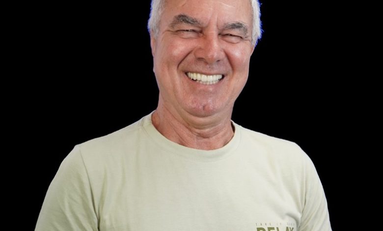 Aarão posa sorrindo para a foto vestindo uma camisa t-short caque