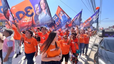 Kelaine cercada de bandeiras em caminhada de campanha em rua de Itaguaí.