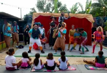 Palhaço e músico com malabaristas e plateia com crianças