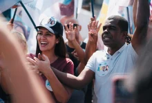 Donizete com Ana Sagário, em meio a bandeiras, fazem campanha em uma rua de Itaguaí