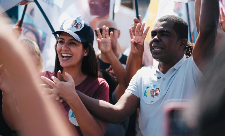 Donizete com Ana Sagário, em meio a bandeiras, fazem campanha em uma rua de Itaguaí