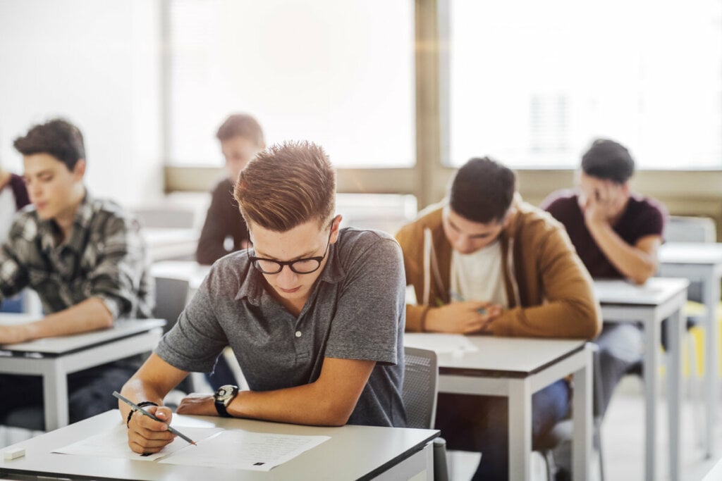 Estudantes sentados em uma sala fazendo prova