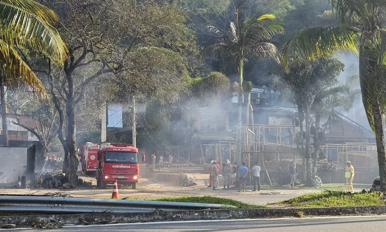 Foto mostra destruição da loja e carro de bombeiro parado ao lado.