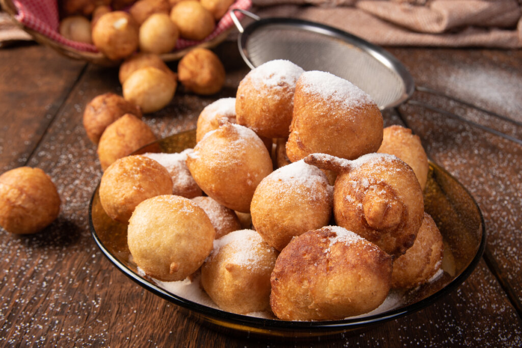 Bolinhos de chuva empilhados em prato de vidro com açúcar