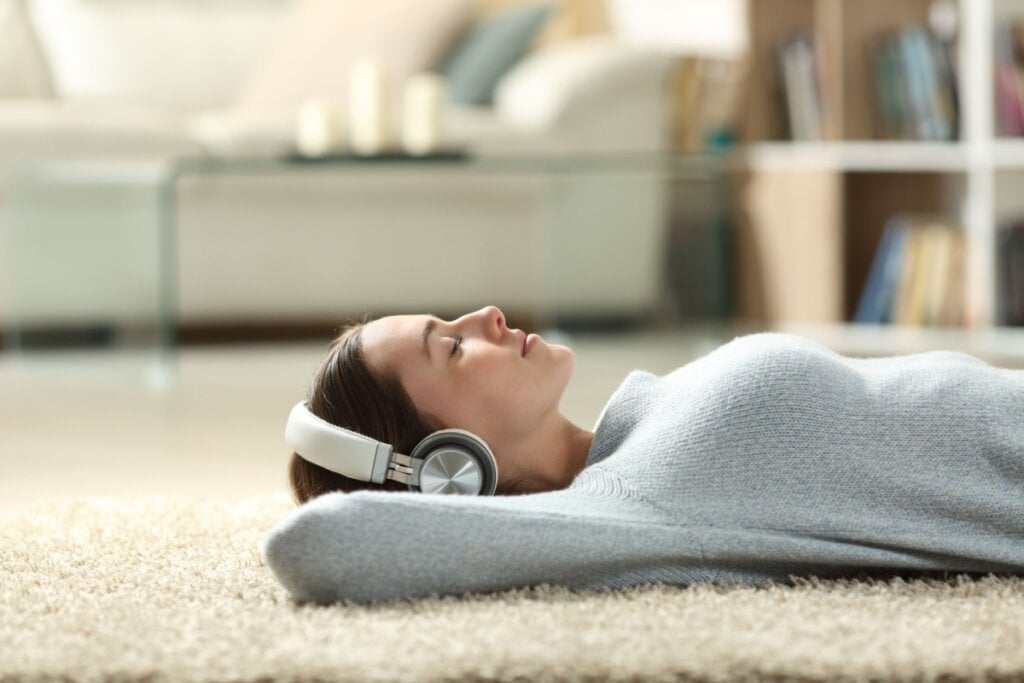 Jovem deitada no chão ouvindo música descansando