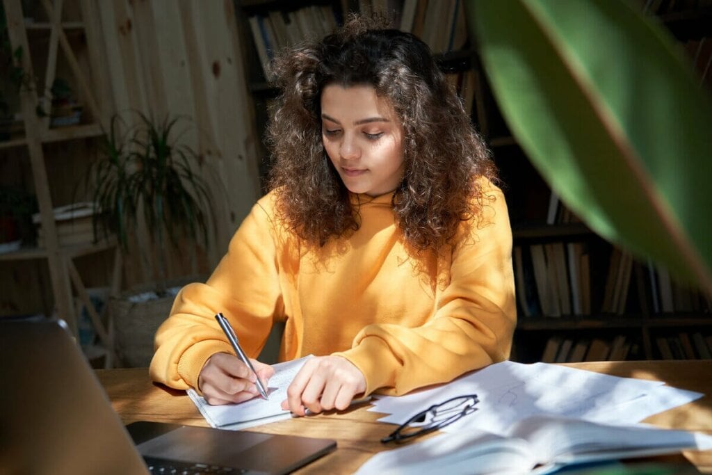 menina escrevendo em papel em sala com sol