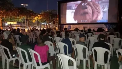 Crianças assistindo o filme Divertidamente 2 ao ar livre.