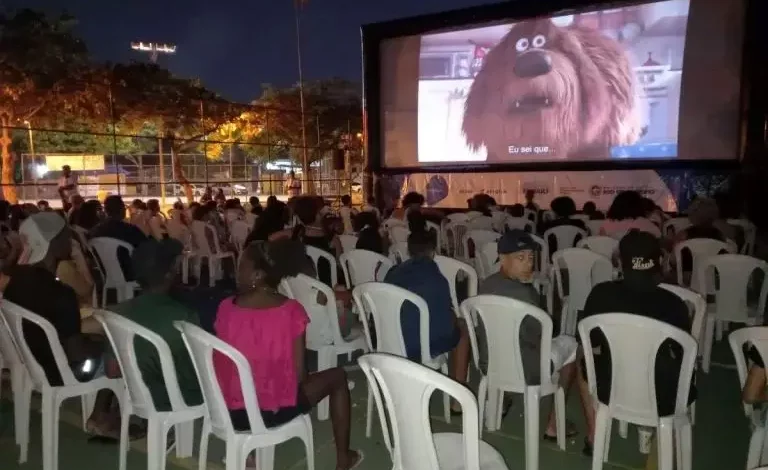 Crianças assistindo o filme Divertidamente 2 ao ar livre.