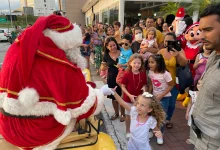 Pais e crianças recebem o Papai Noel no shopping