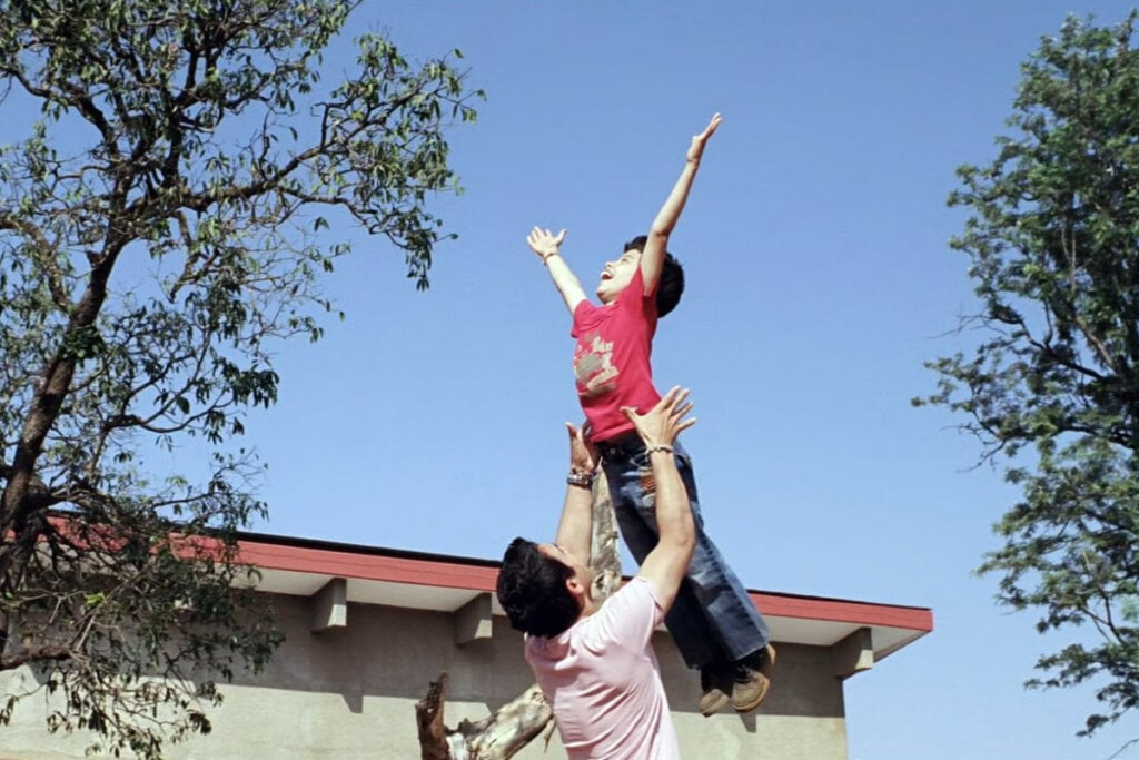 Homem jogando criança sorrindo pra cima 