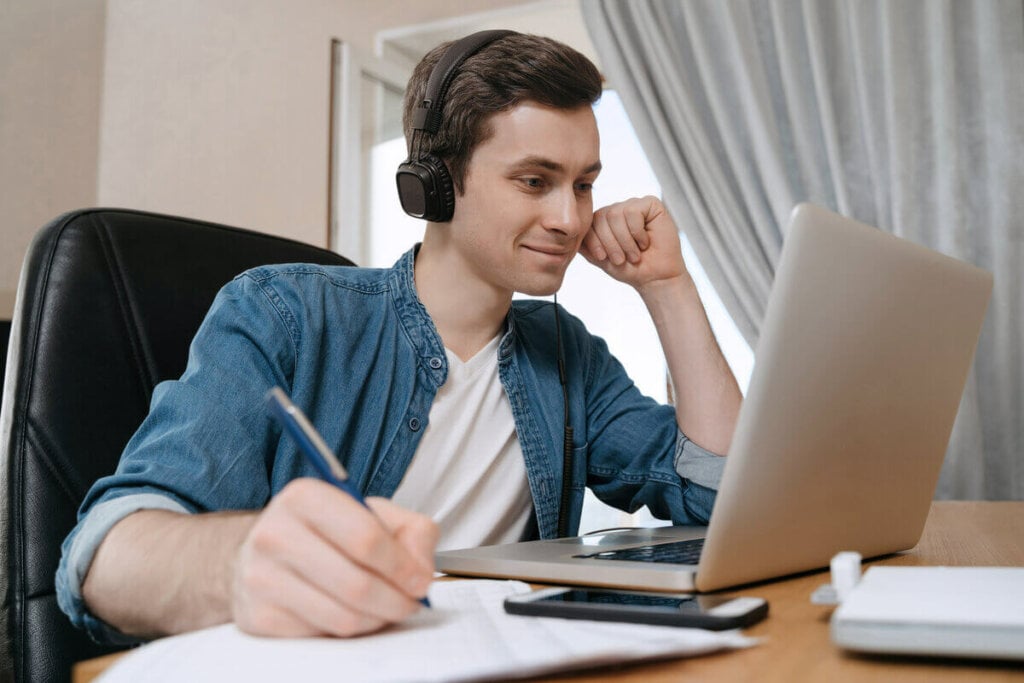 Rapaz estudante com notebook e fazendo anotações