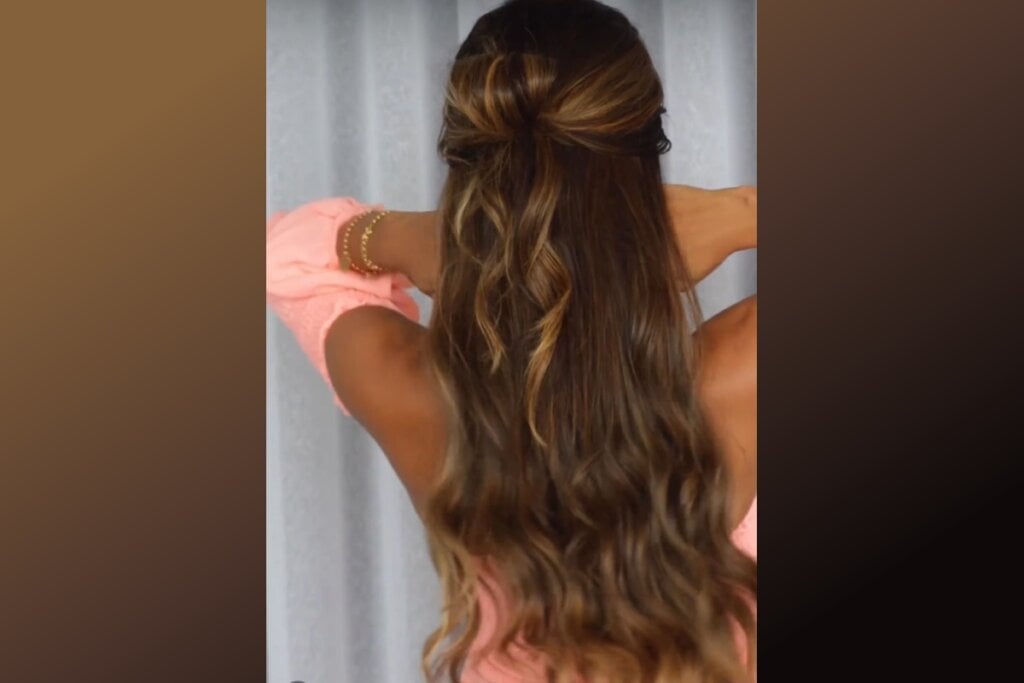 Mulher com cabelo meio-preso, exibindo uma textura ondulada e laço com cabelo