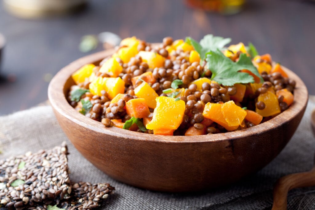 Salada de lentilha com abóbora e cenoura em recipiente marrom