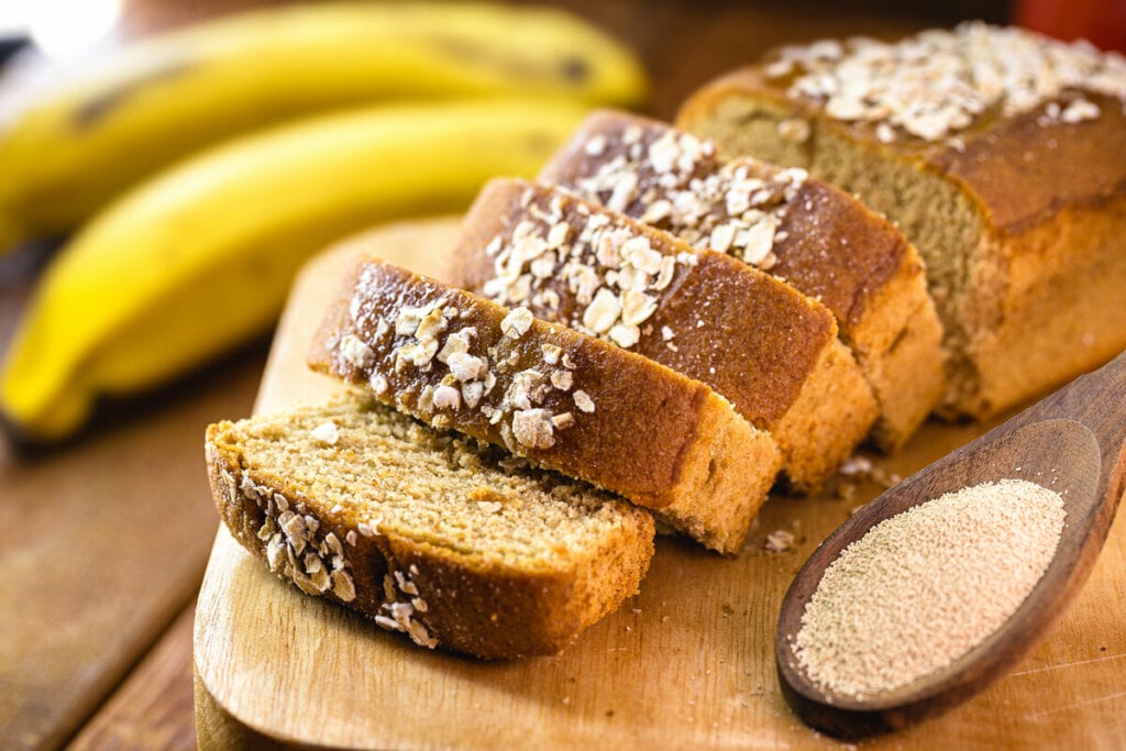 Bolo de banana cortado em pedaços em cima de uma tábua de madeira