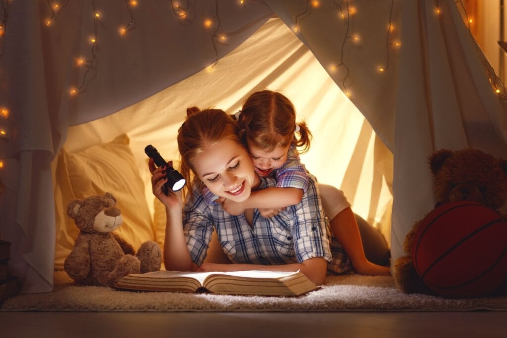 Mãe e filha lendo em cabana no quarto 