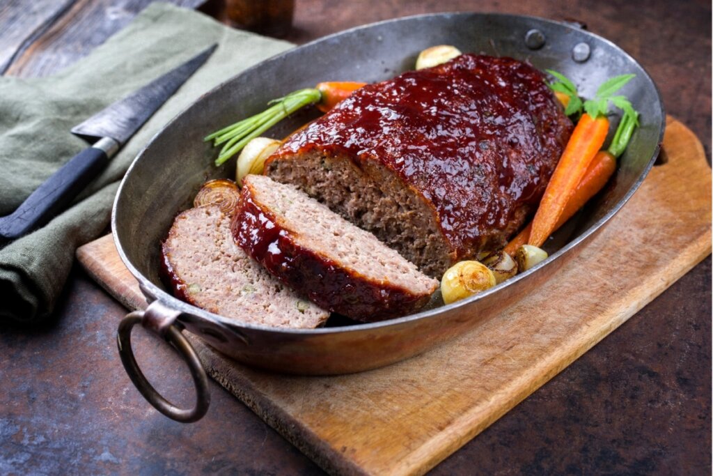 Bolo de carne em um recipiente metálico com cenoura cozida e cebola caramelizada 