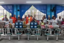 Pessoas diante de uma grande mesa com várias doações em cima