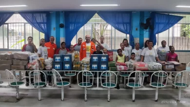 Pessoas diante de uma grande mesa com várias doações em cima