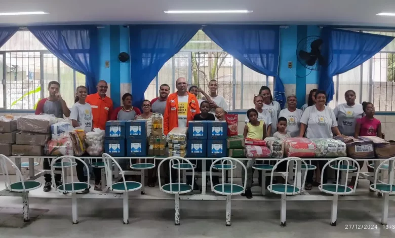 Pessoas diante de uma grande mesa com várias doações em cima