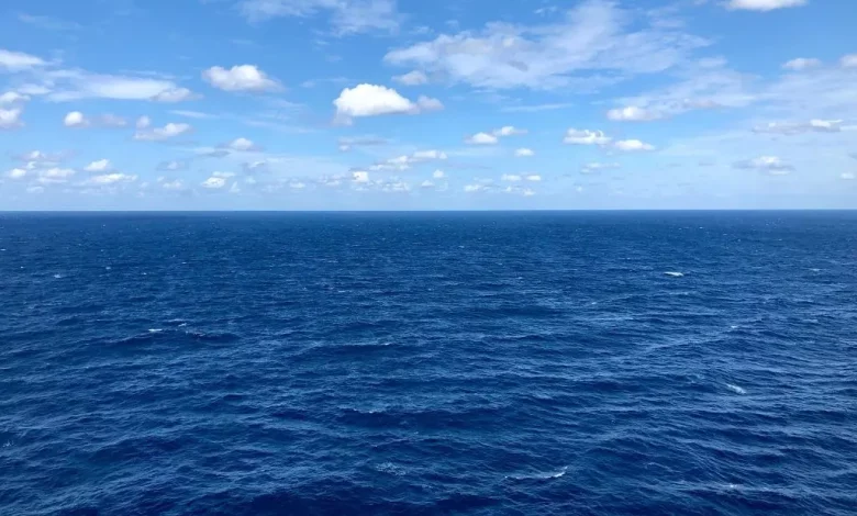 Vista panorâmica do oceano azul sob um céu com nuvens dispersas