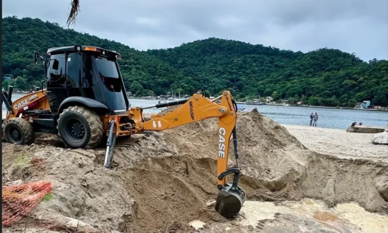 Máquina retroescavadeira realizando obras de saneamento na orla de Itacuruçá