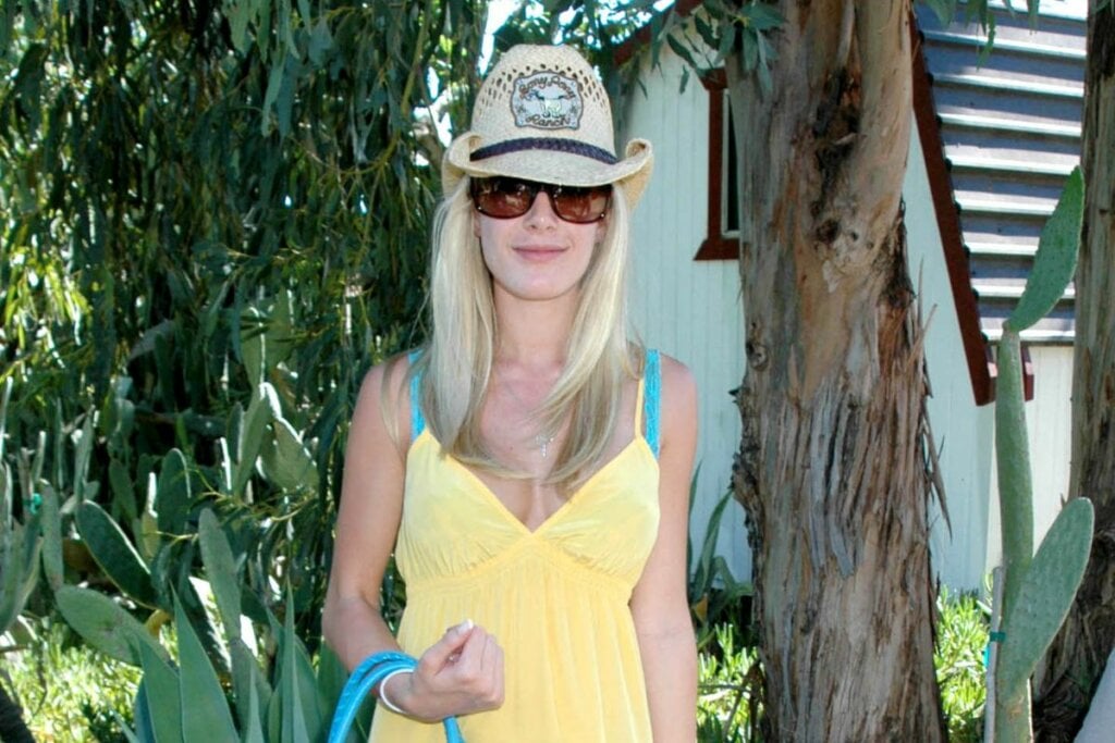 Mulher usando um vestido amarelo e chapéu de palha cowboy posando para foto 