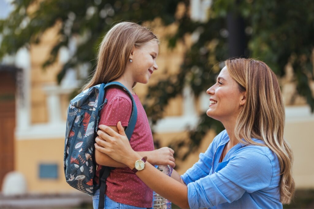 Mãe deixando filha na escola no retorno as aulas