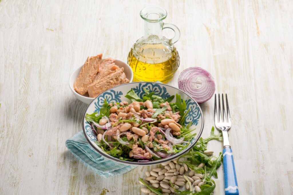 prato branco e azul com salada de feijão-branco, atum, rúcula e cebola-roxa