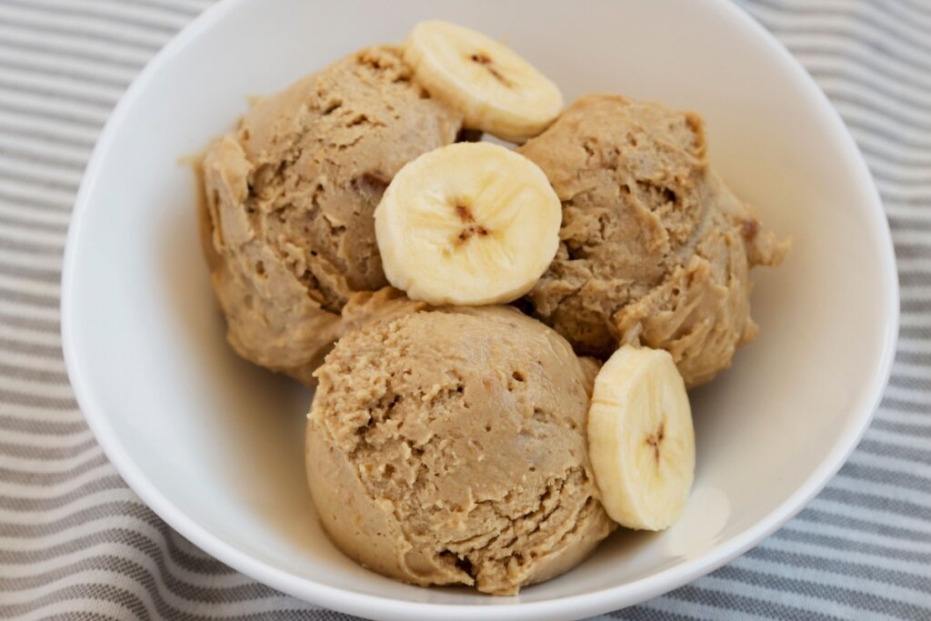 Sorvete de banana com amendoim servido em tigela branca com rodelas de banana 