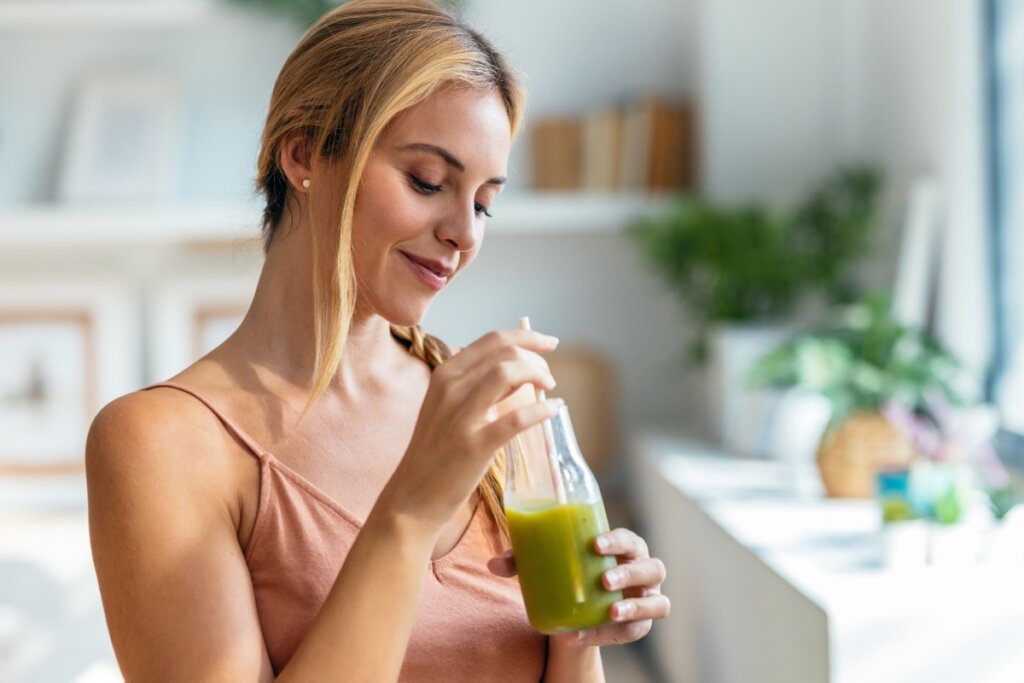 Mulher loira bebendo suco verde