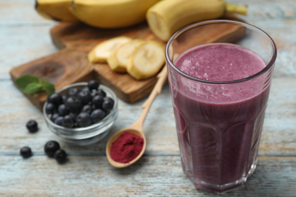 Copo de vitamina ao lado de banana e açaí