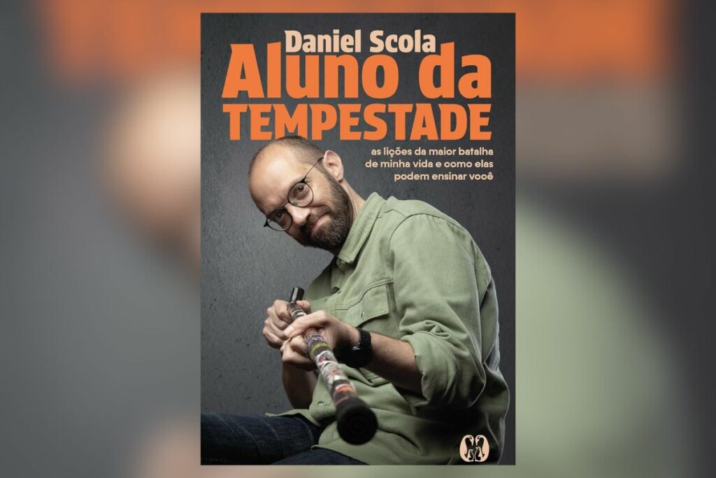 Capa de livro com título e nome do autor em laranja e com a imagem de um homem sentado apontando uma bengala para a foto