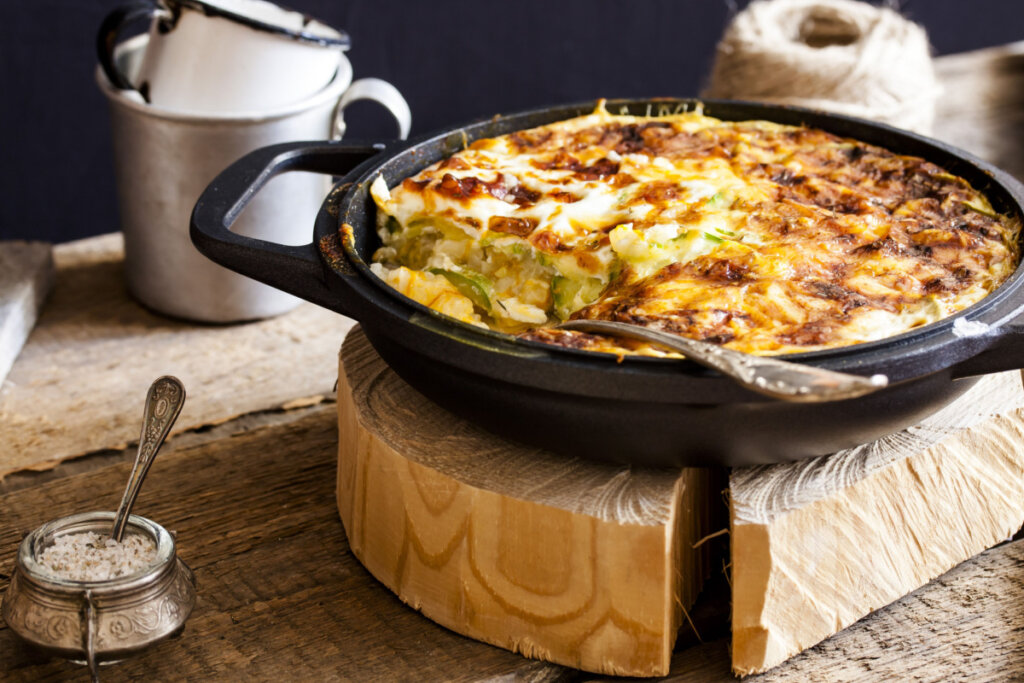 Arroz gratinado com abobrinha em panela preta em cima de madeira