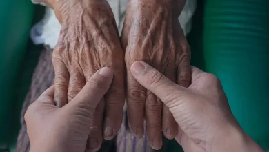 Uma pessoas segurando as mãos de uma idosa