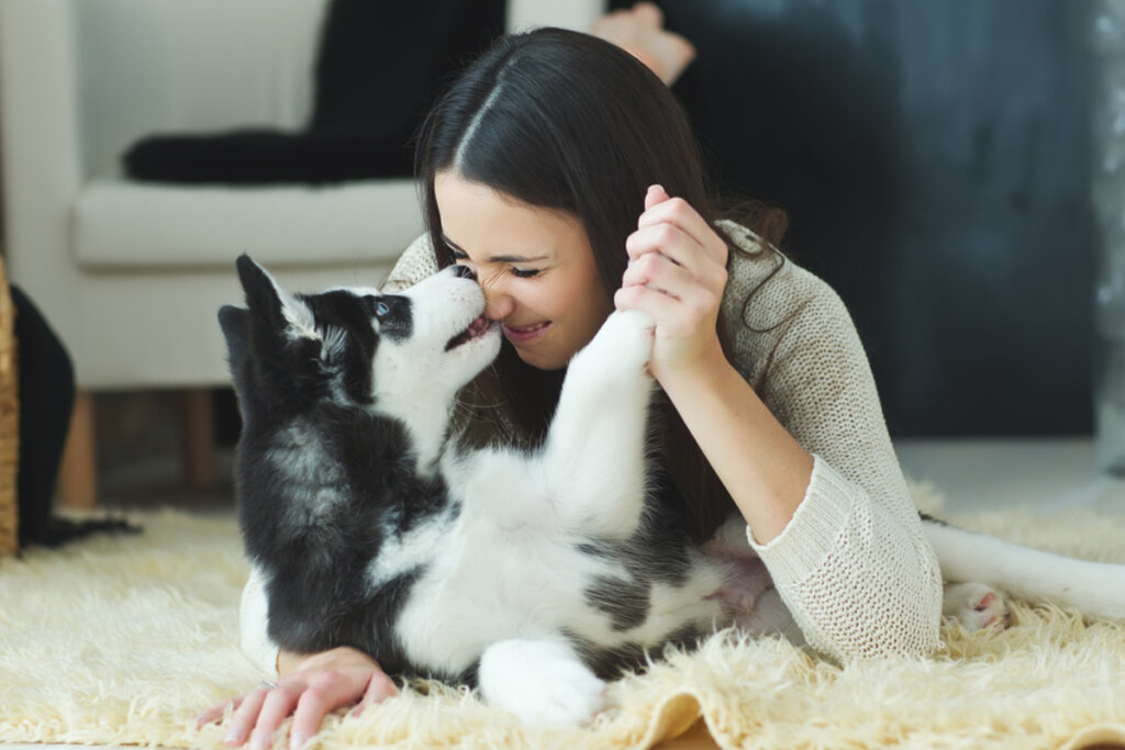 Mulher deitada brincando com um cachorro