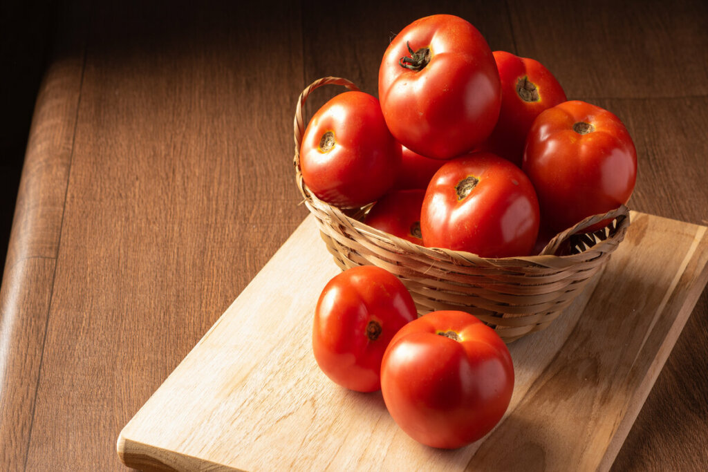 Cesta com tomate em cima de uma tábua de madeira