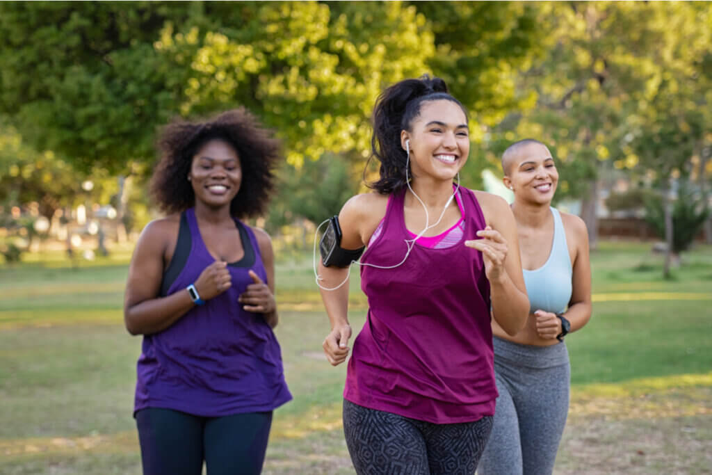 Três amigas sorrindo e correndo em parque