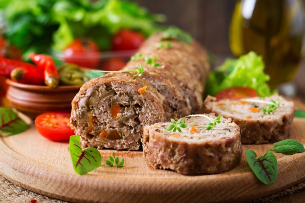 Rocambole de carne moída com cenoura em cima de uma tábua de madeira 