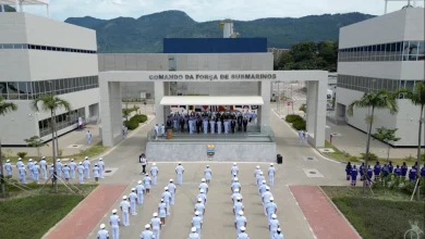 Marinha do Brasil expande Complexo Naval de Itaguaí - foto aérea mostra cerimonial. No primeiro plano, militares estão em posição de sentido enfileirado. No cenário, ao centro tem um portal com a inscrição "comando da força de submarinos" entre dois prédios administrativos, onde estão os militares de alta patente