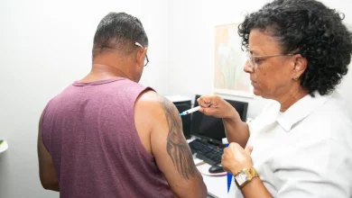 Itaguaí vacinação sarampo / foto mostra enfermeira aplicando vacina em um homem, que aparece de costas com blusa t-shirt