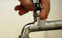 Mão abrindo torneira sem água