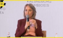 Mulher sentada segura microfone durante sua fala em uma palestra