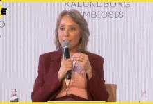 Mulher sentada segura microfone durante sua fala em uma palestra