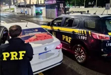 Agente da PRF ao lado de veículo apreendido com tabletes de cocaína