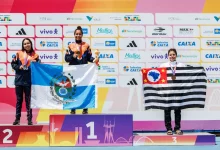 Atletas do Time RJ celebram no pódio com a bandeira do Estado do Rio de Janeiro após conquista de medalhas