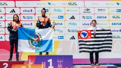 Atletas do Time RJ celebram no pódio com a bandeira do Estado do Rio de Janeiro após conquista de medalhas